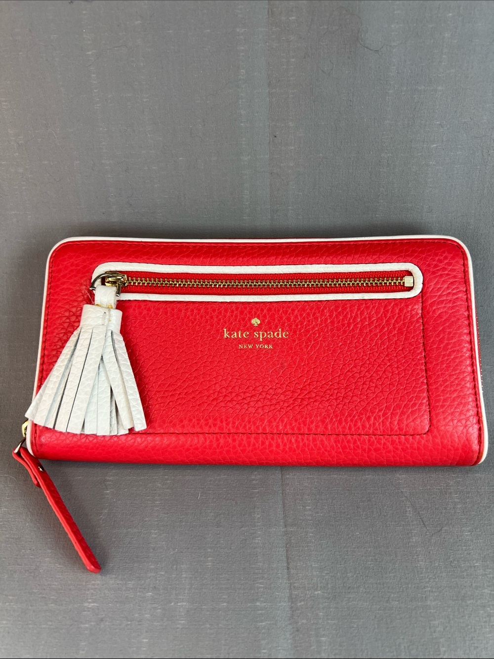 Kate Spade melon color, leather wallet with white leather trim and tassel.